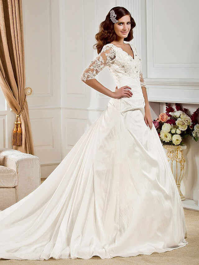 Close-up of V-neckline and half sleeve with beading on wedding dress.