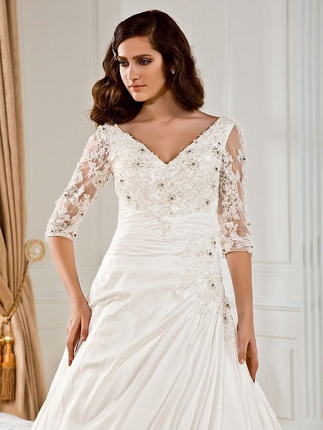 Detailed view of ruched bodice and appliques on wedding gown.