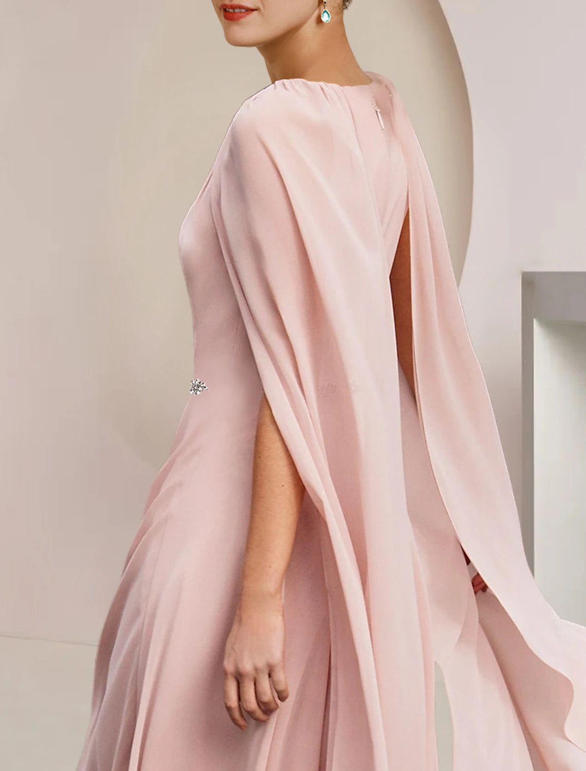 Close-up of the crystal brooch and pleated detail on the chiffon dress.