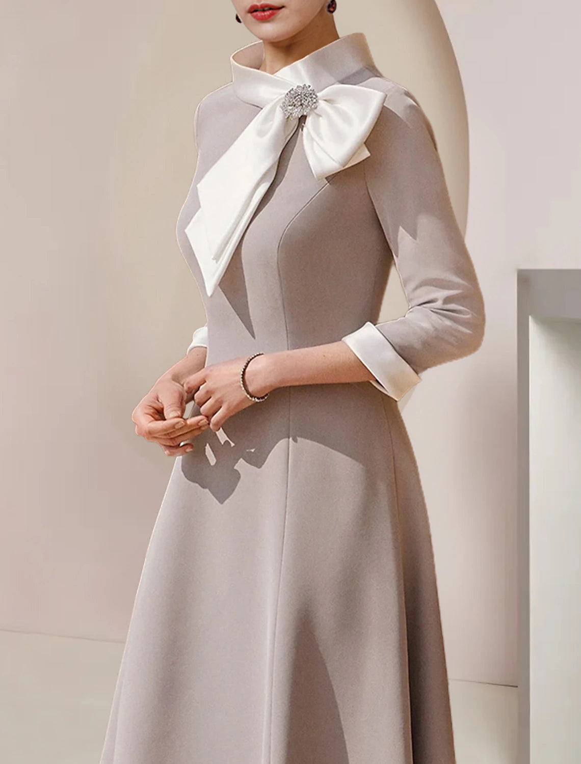 Side view of high neck satin dress, showing 3/4 sleeves and asymmetrical hem.