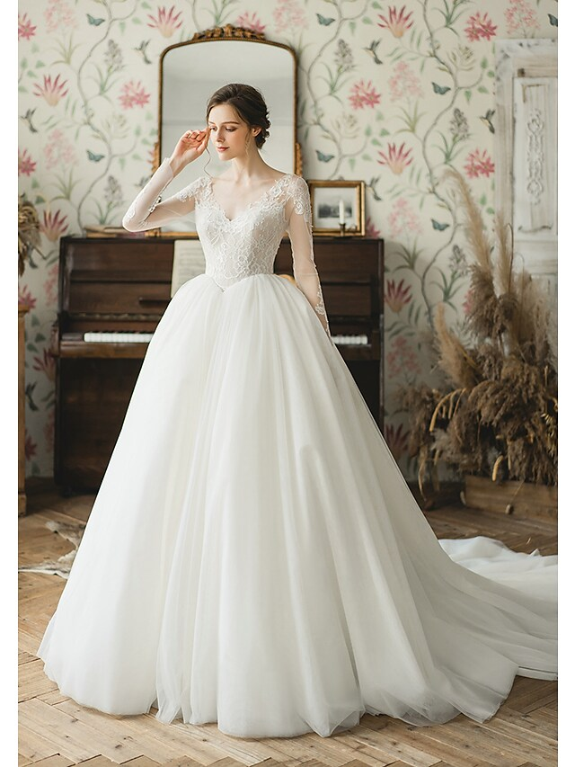 Bride wearing a Luolandi elegant ball gown wedding dress with V-neck and long tulle sleeves.