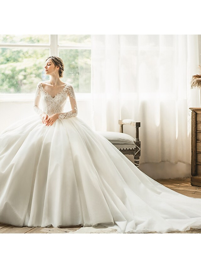 Side profile of a bride in a long sleeve tulle ball gown wedding dress.