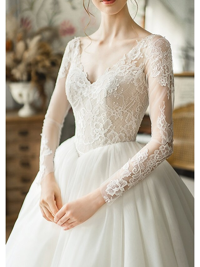 Detail of the long tulle sleeves and fabric texture of the wedding gown.