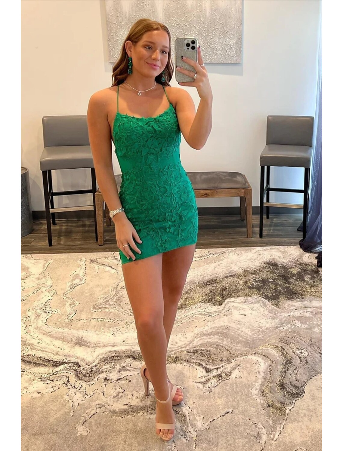Model wearing a short mermaid trumpet homecoming dress with spaghetti straps and appliques.